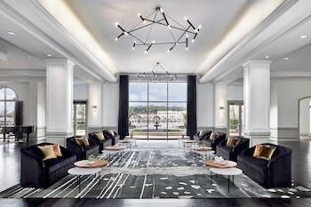 A group of people sitting on a sofa in a room with striped curtains and a wooden floor. at The Westin Savannah Harbor Golf Resort & Spa