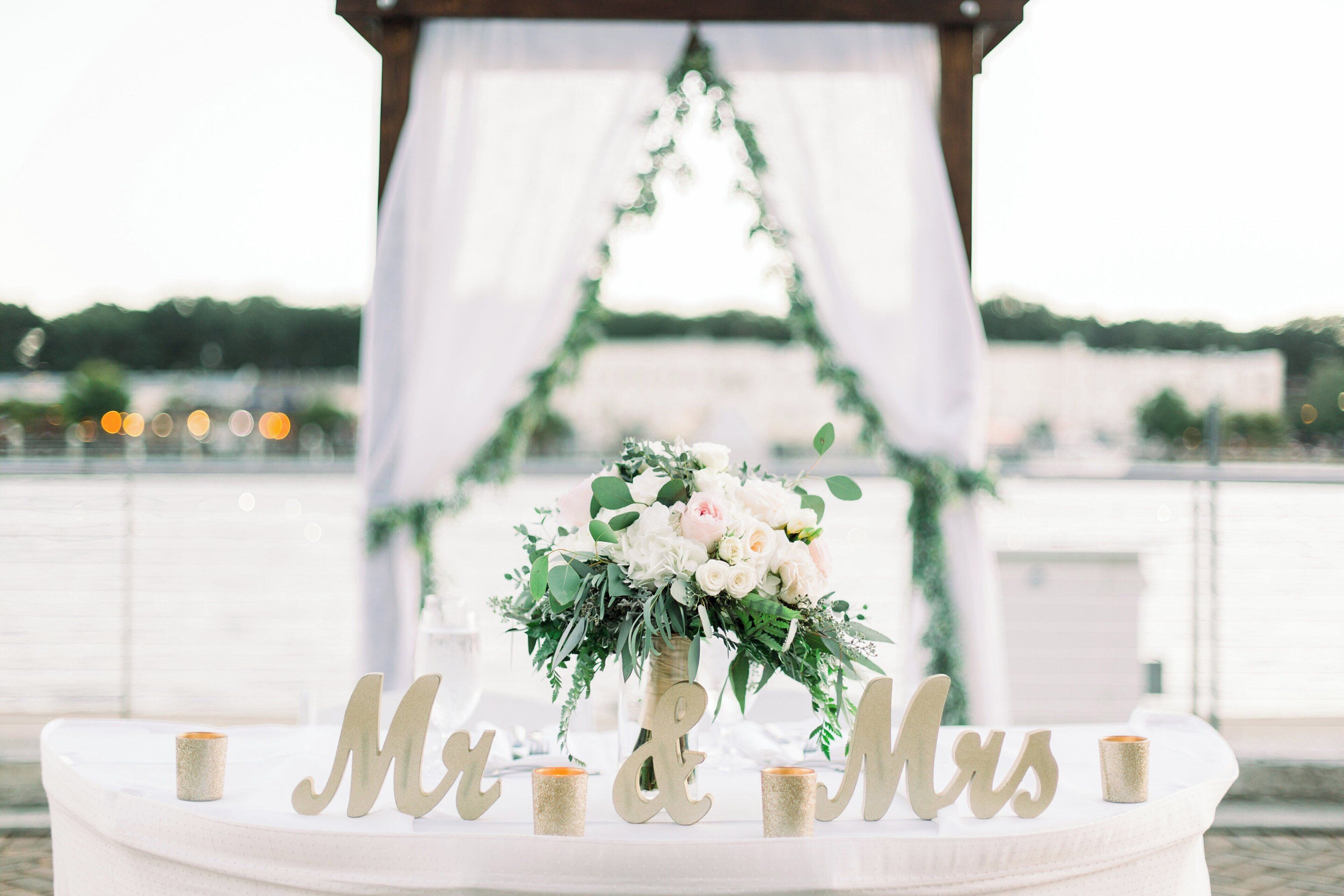 Un arco de boda con una decoración floral y la inscripción 'Mr & Mrs' sobre una mesa con velas.