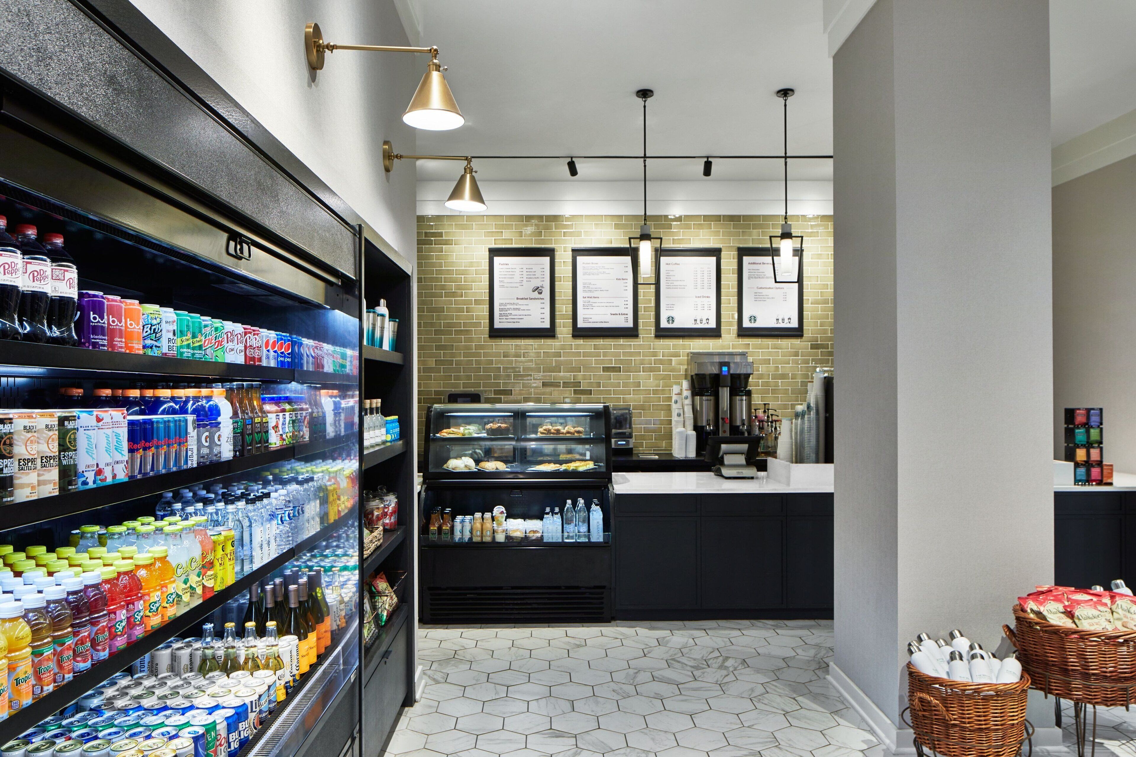 A modern cafe with a refrigerated beverage display, a coffee station, and a menu board.