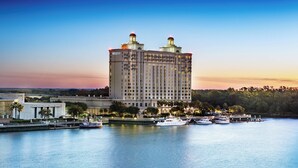 Ein großes Hotel mit Blick auf das Wasser, mehrere Boote im Hafen und ein klarer Himmel.