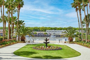 A waterfront garden with a fountain, palm trees, and a building in the background. - The Westin Savannah Harbor Golf Resort & Spa (Savannah)