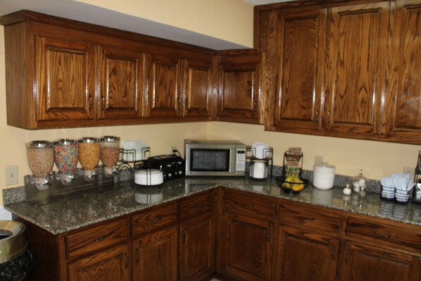 A kitchen with wooden cabinets, a granite countertop, and various appliances including a microwave and coffee maker.