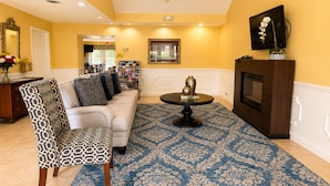Una sala de estar con sofá, sillón estampado, mesa de centro y chimenea.
