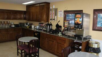 Una cocina con armarios de madera, un microondas, una cafetera y un refrigerador.