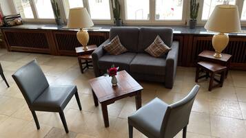 A cozy seating area with a sofa, two armchairs, and a small table with a vase of flowers.