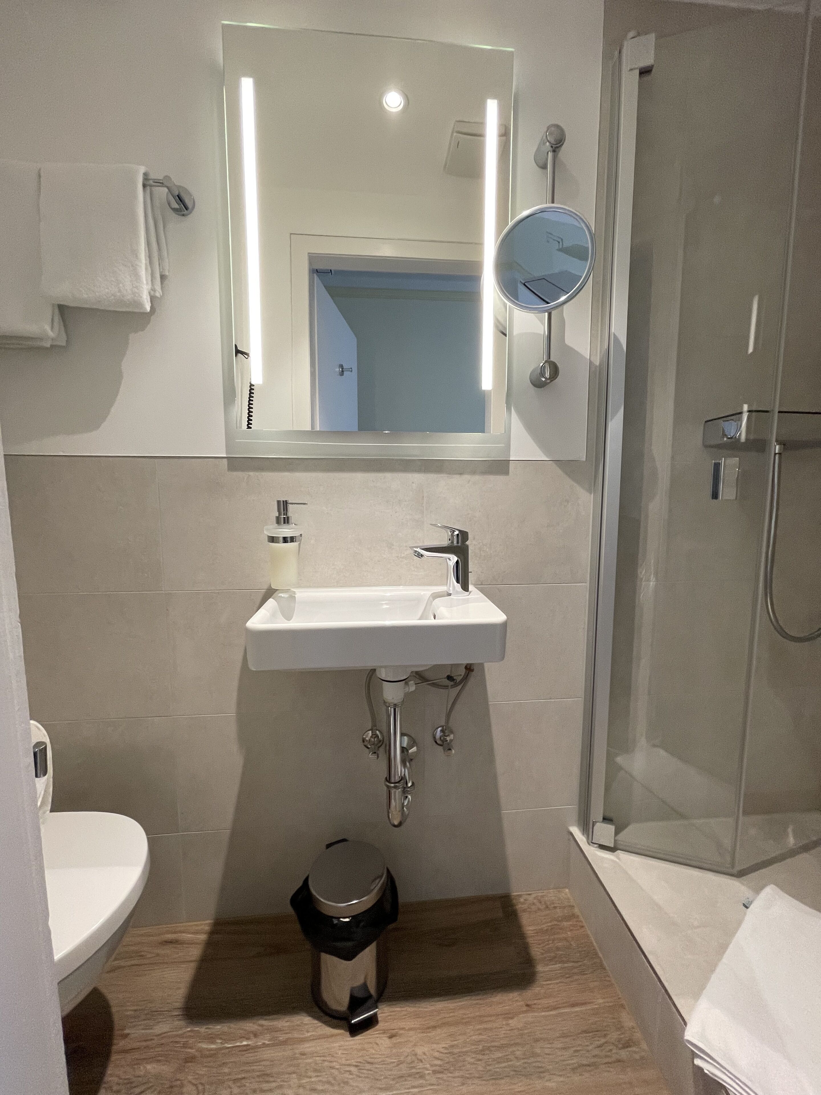A bathroom with a white sink, mirror, and shower.