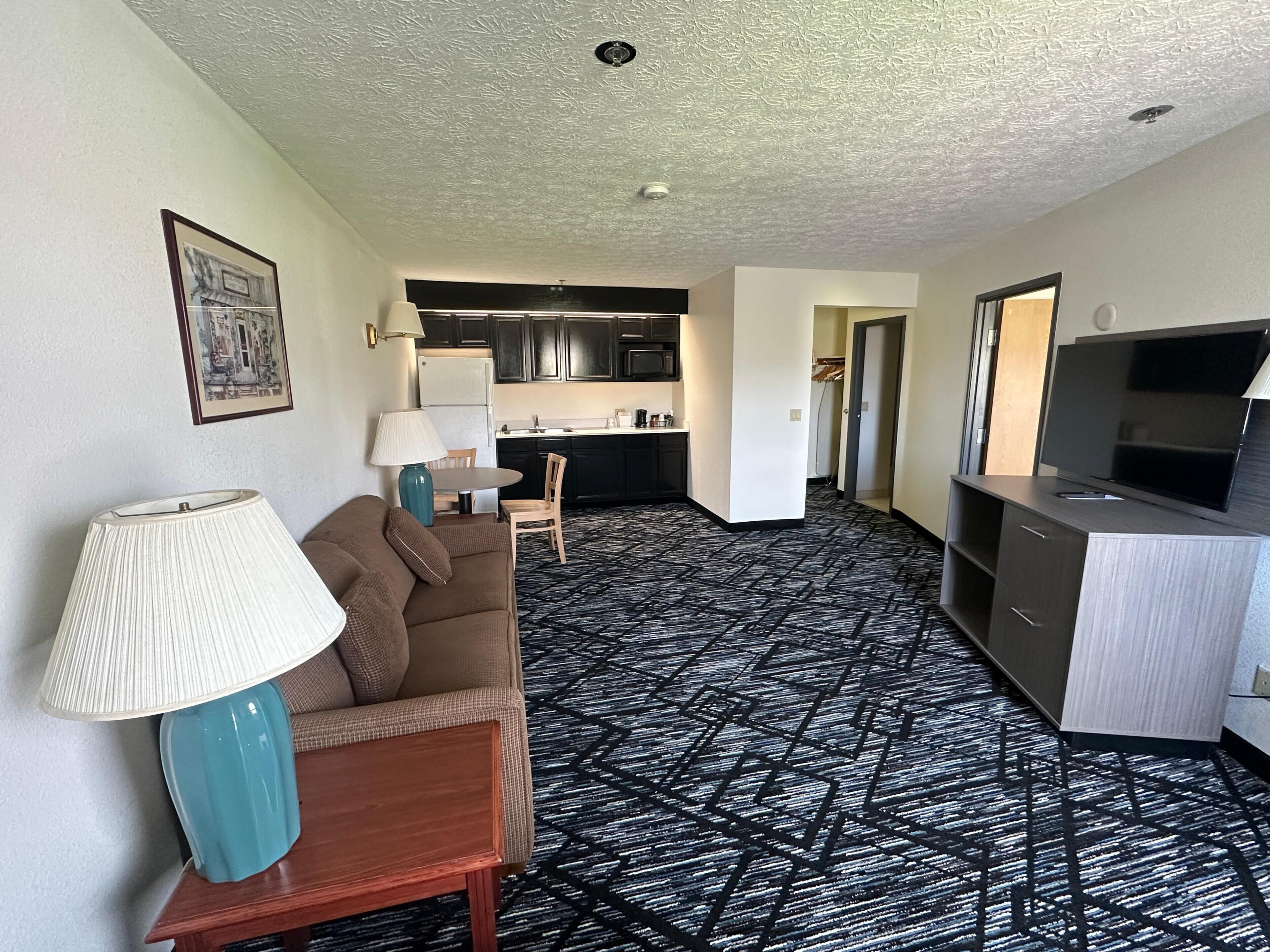 Una habitación de hotel moderna con zona de estar, kitchenette y televisor.