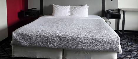 Una habitación de hotel con una cama, un escritorio, una lámpara y un cuadro en la pared.