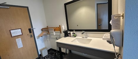 A hotel bathroom with a large mirror, a sink, a telephone, and a towel rack.