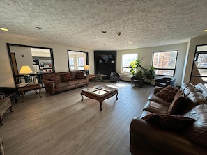 A spacious living room with a fireplace, leather sofas, a coffee table, and large windows offering views of the outside. - Ramada by Wyndham Strasburg Dover (Strasburg)