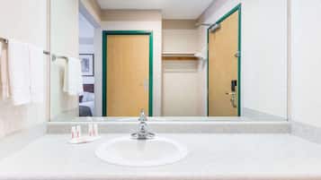 A hotel bathroom with a large mirror, a sink, and a door with green trim.