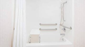 A white bathroom with a shower, grab bars, and a white sink.
