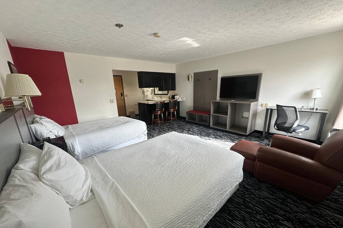 Habitación de hotel con dos camas, un escritorio, un televisor y una silla.