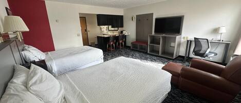 Habitación de hotel con dos camas, un escritorio, un televisor y una silla.