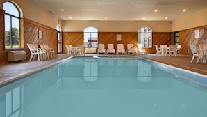 En swimmingpool med liggestole og udsigt til det fri.