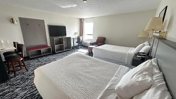 Habitación de hotel con dos camas, un escritorio, un televisor, una silla y una ventana.