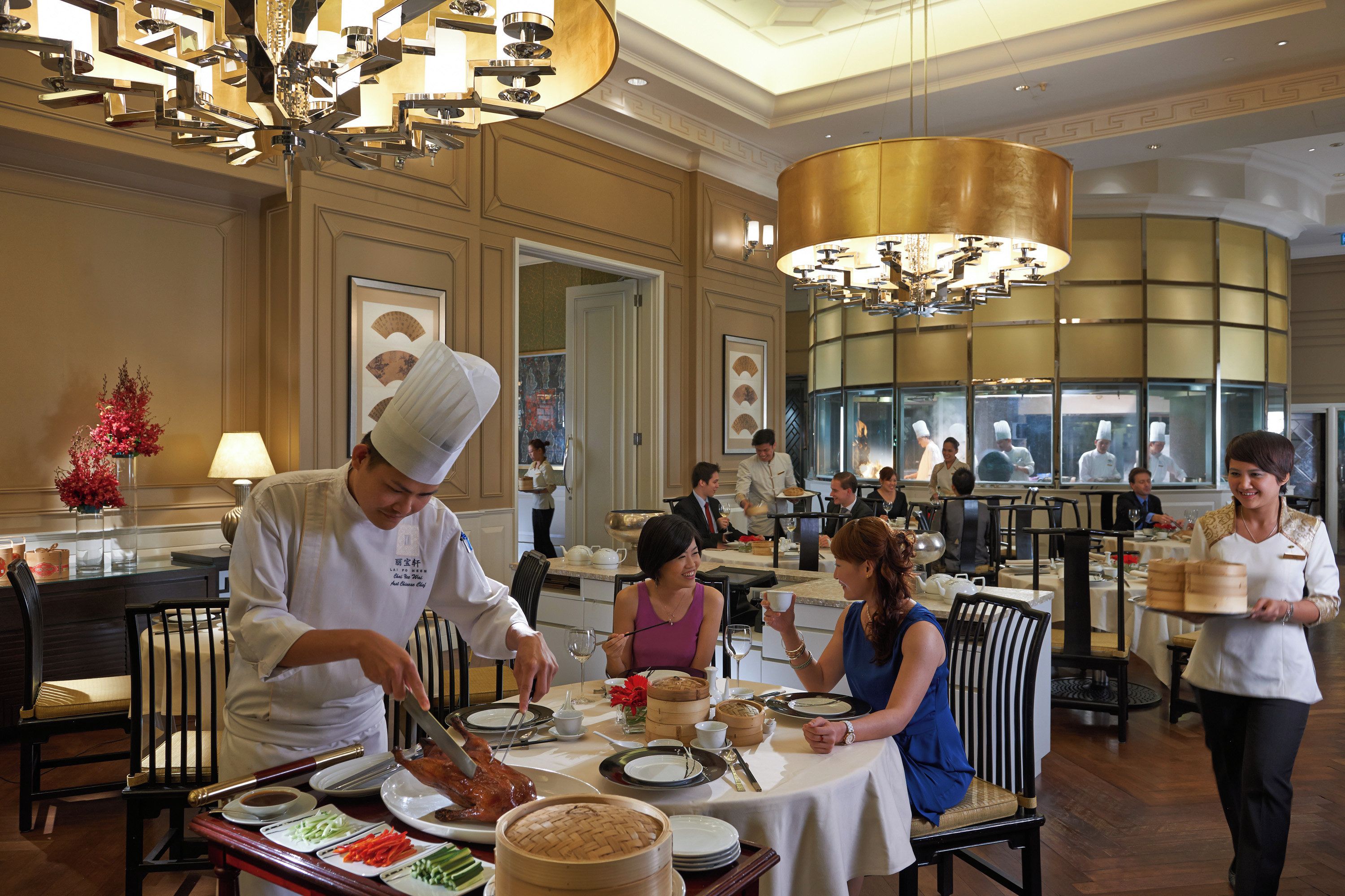 A restaurant interior with a chef preparing food, diners seated at tables, and a waiter serving dishes.