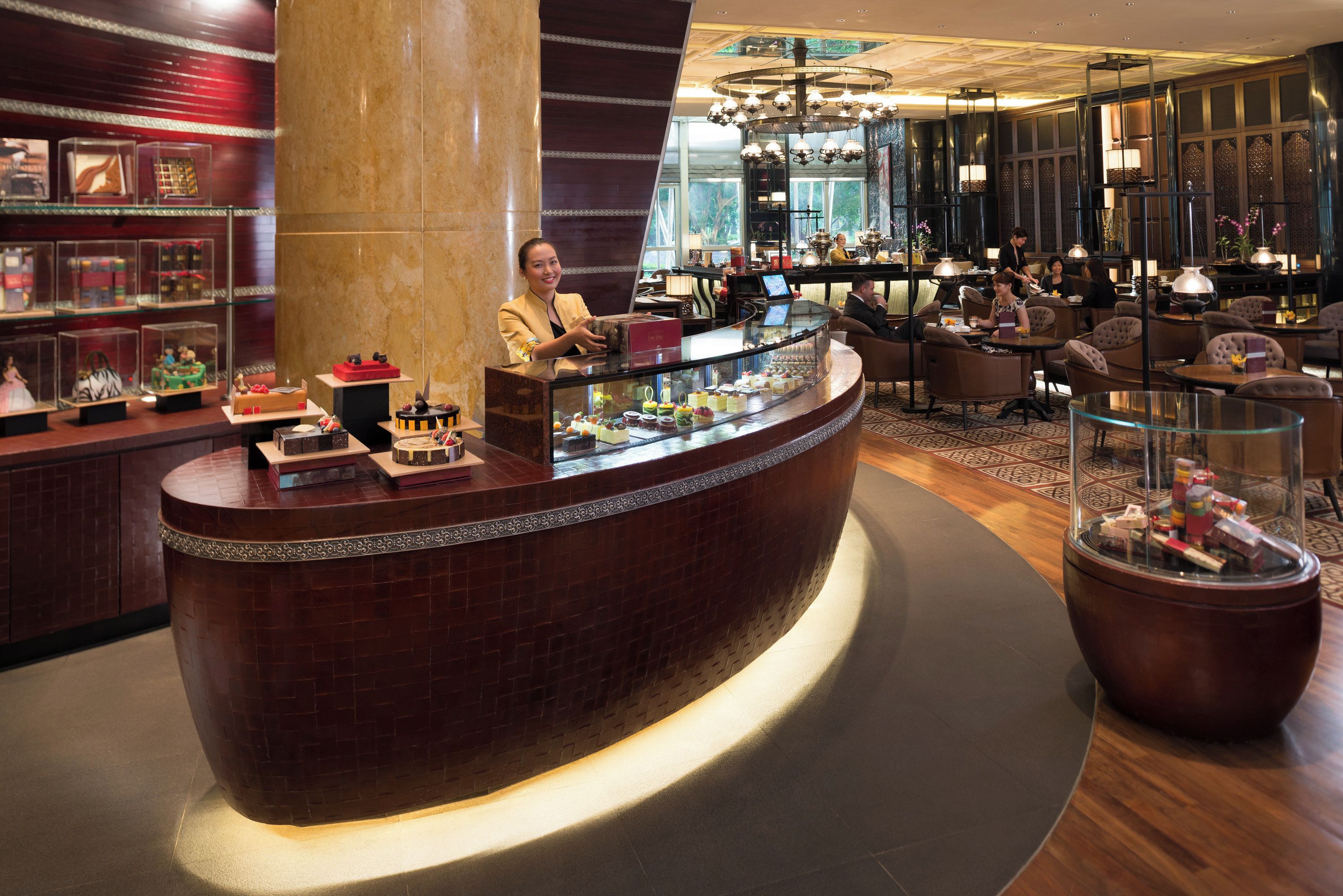 Eine Hotelhalle mit einer gebogenen Rezeption, einer Sitzecke und einem großen Chandelier.