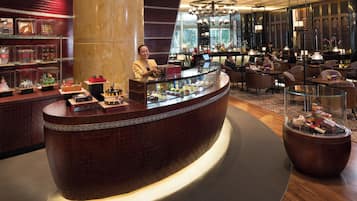 A hotel lobby with a curved reception desk, seating area, and a large chandelier.