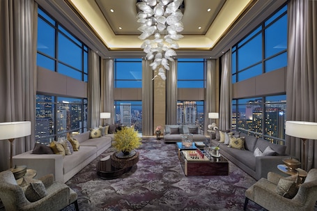 A spacious living room with a large window, a chandelier, and a sofa set.