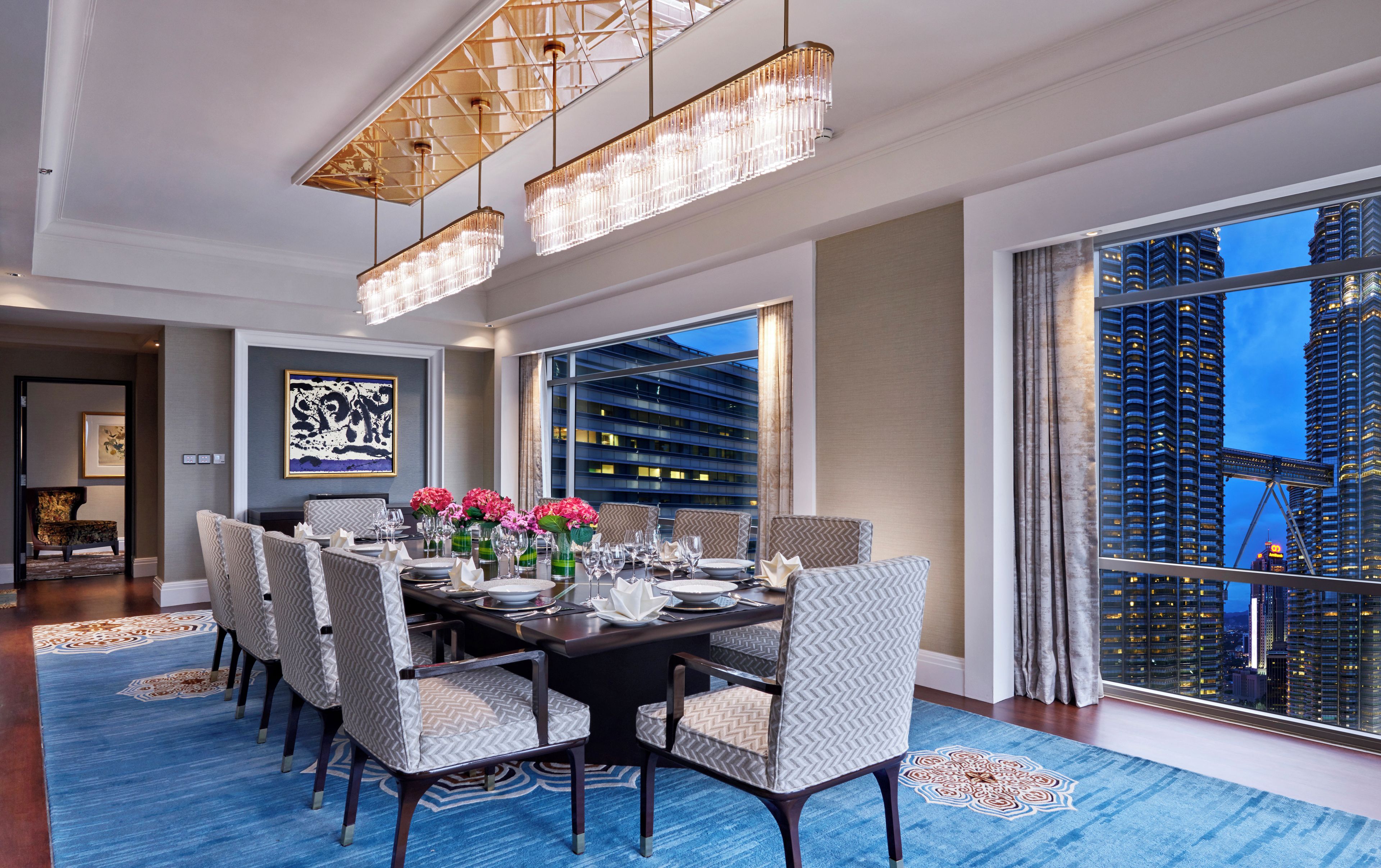 A dining area with a table set for six, large windows, and a view of a cityscape.