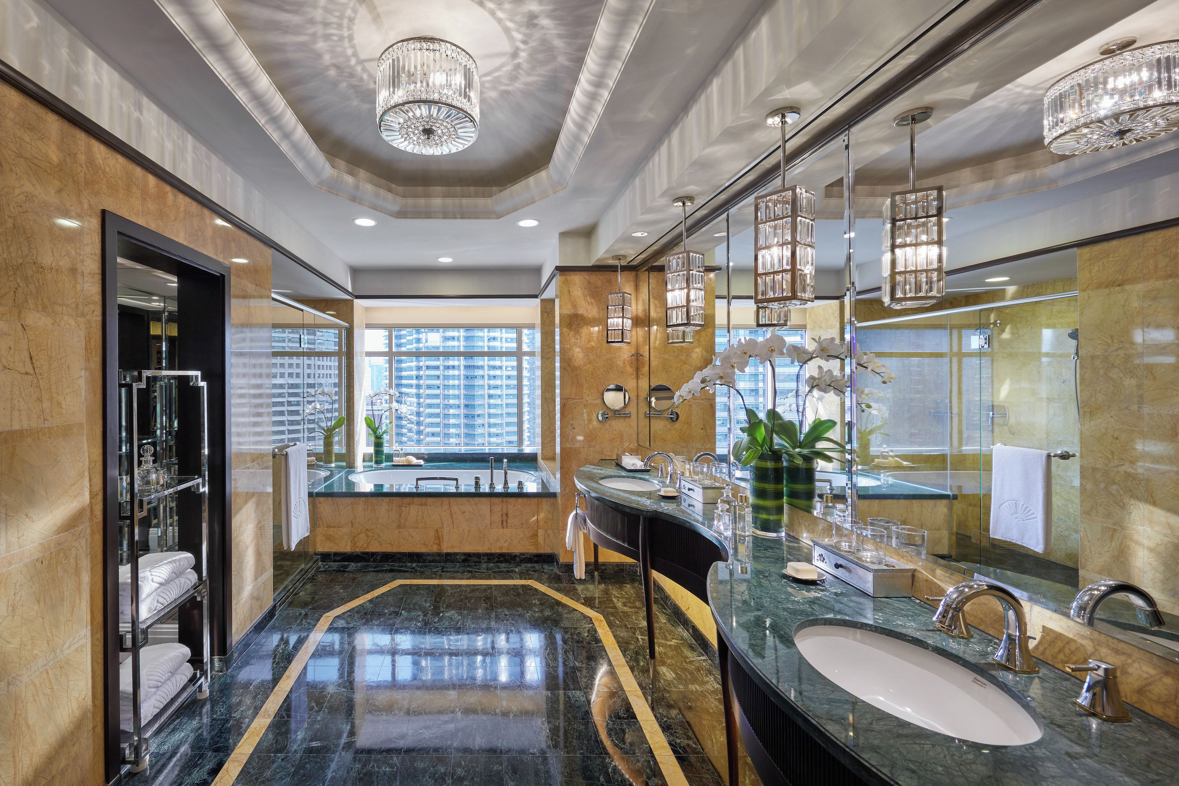 A luxurious bathroom with a large mirror, marble flooring, and a view of the cityscape.