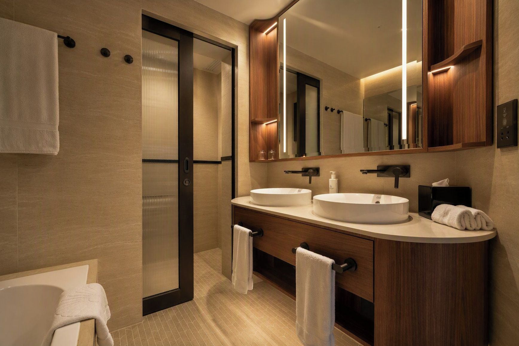 A modern bathroom with two sinks, a large mirror, and a walk-in shower.