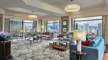 A spacious hotel living room with a large city view, modern furniture, and decorative elements.