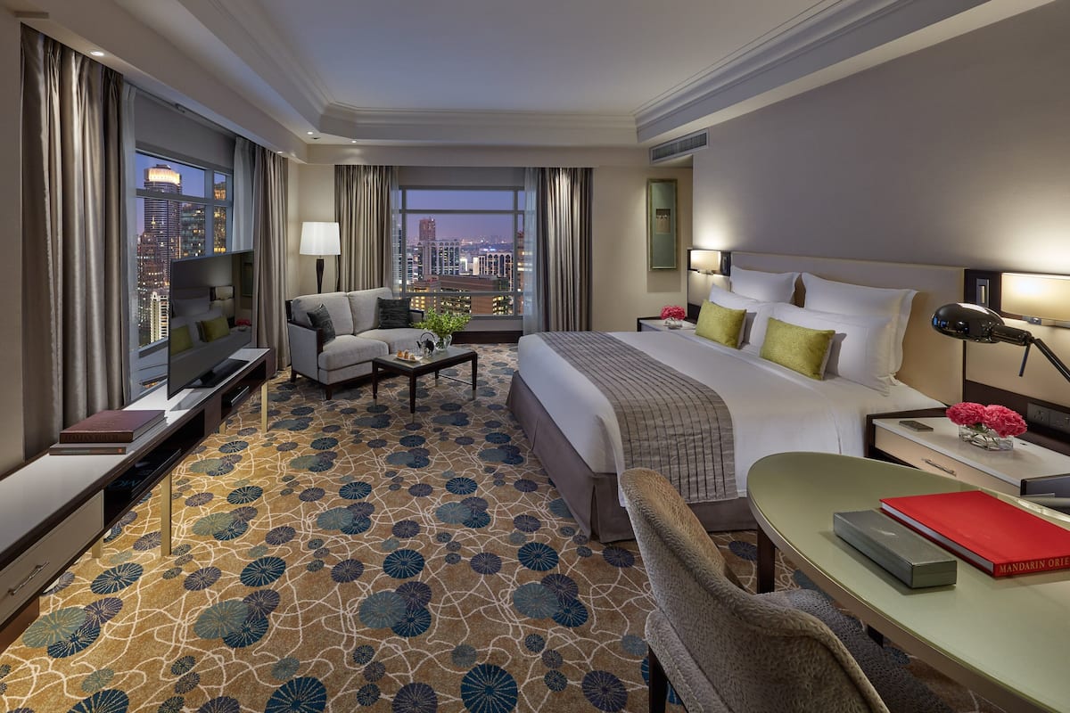 Ein Hotelzimmer mit einem großen Bett, einem Schreibtisch, einem Fernseher und Blick auf die Stadt.