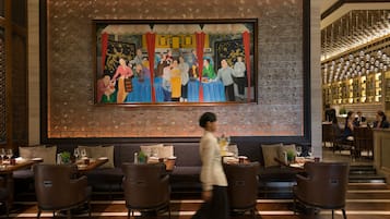A restaurant with a large mural on the wall, wooden furniture, and a modern interior design.
