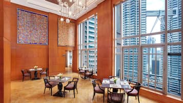 A spacious hotel lobby with large windows, a high ceiling, and a modern chandelier.