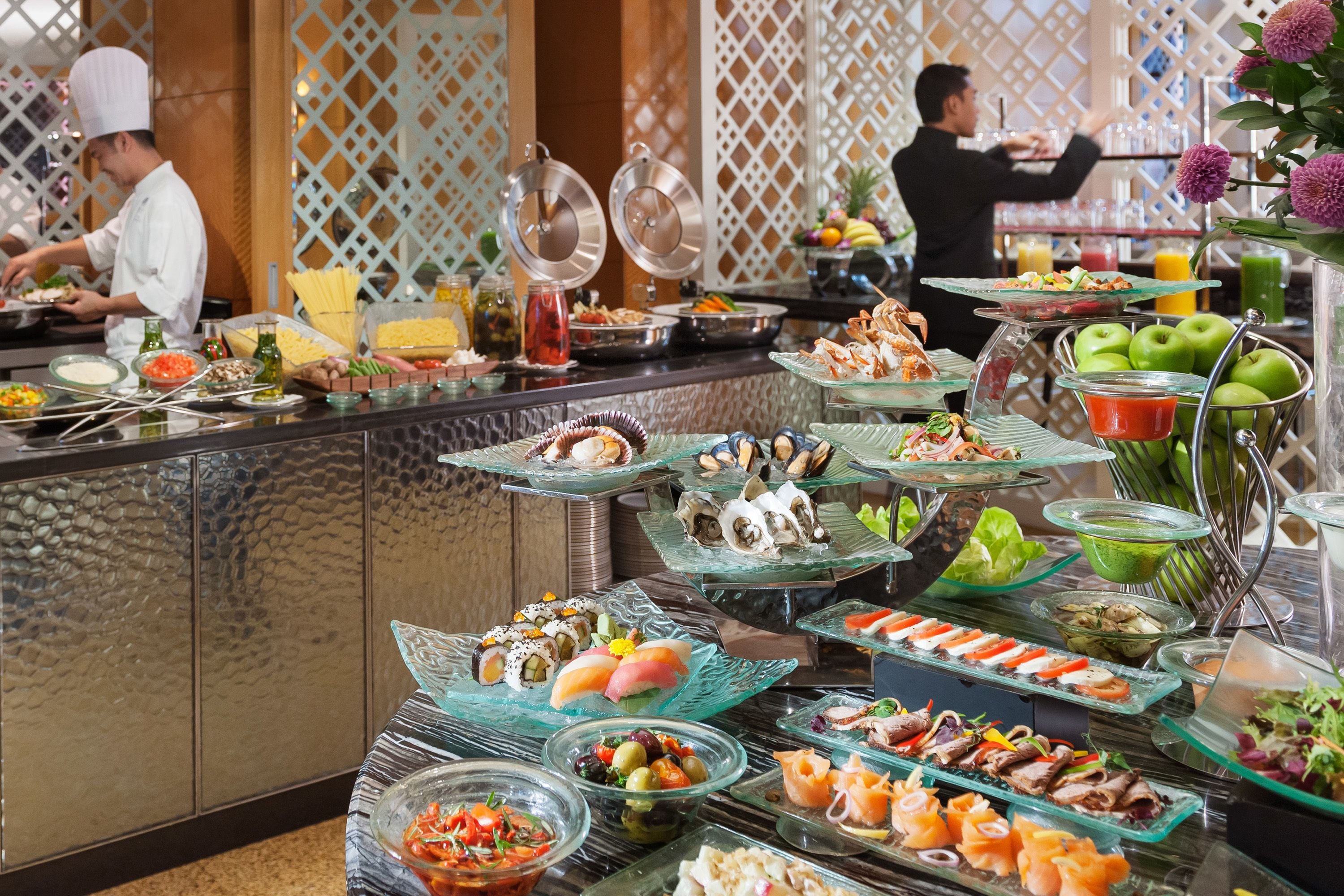A buffet with various food items and a chef preparing food.