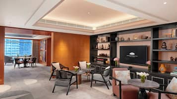A modern lounge area with seating, a television, and decorative items.