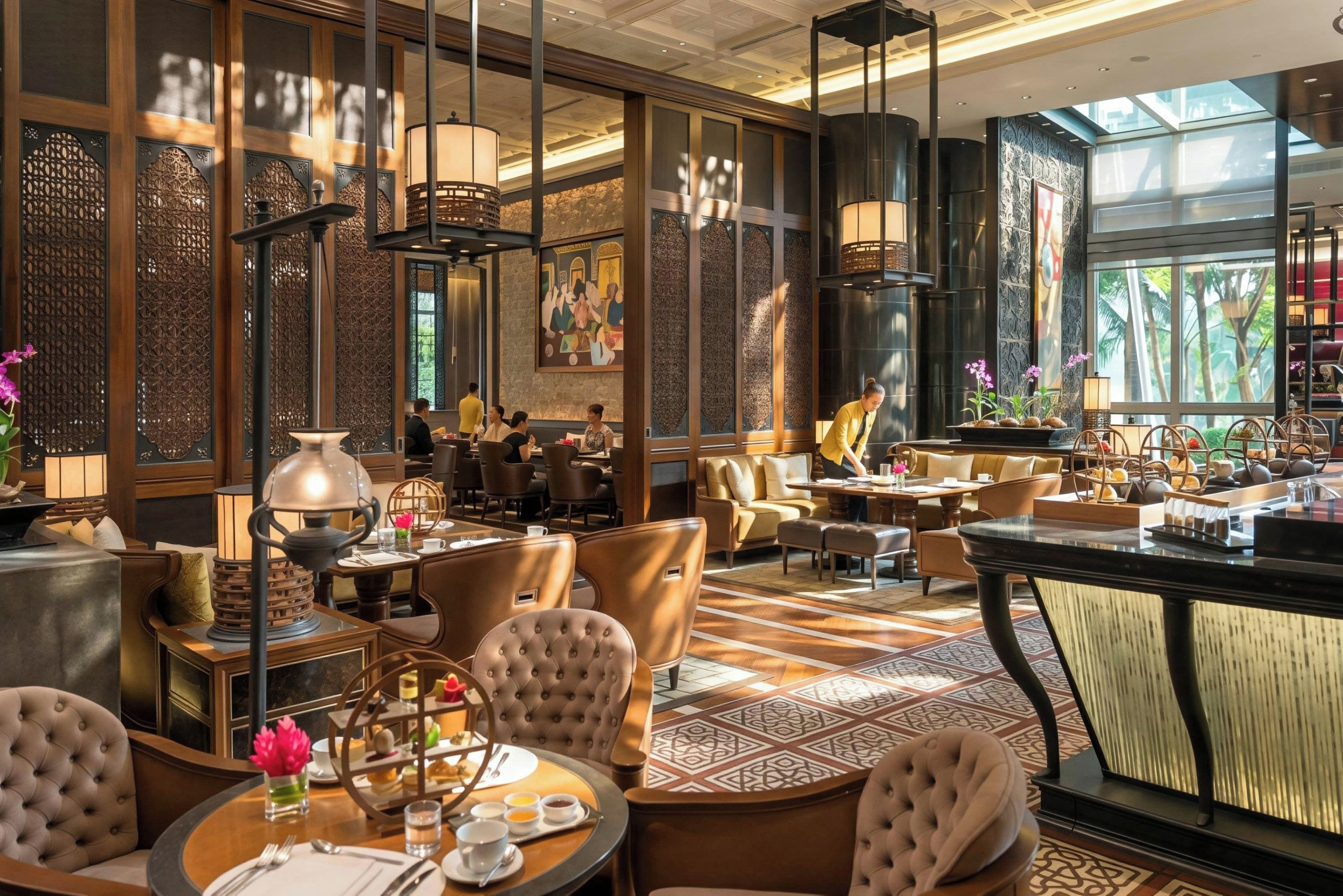 A restaurant with high ceilings, ornate wooden panels, and a variety of seating arrangements including tables and chairs.