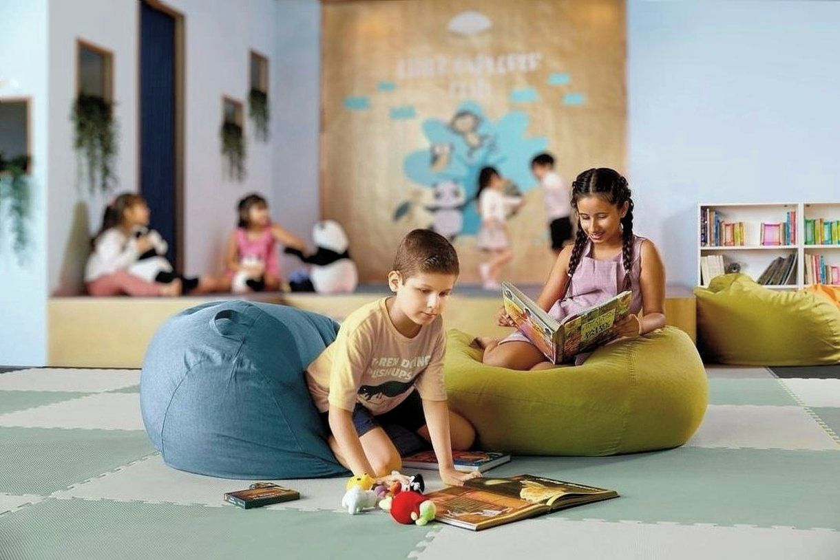 A children's play area with bean bags and toys, a bookshelf, and a mural on the wall.