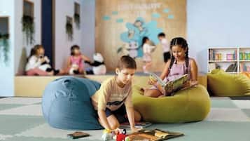 A children's play area with bean bags and toys, a bookshelf, and a mural on the wall.