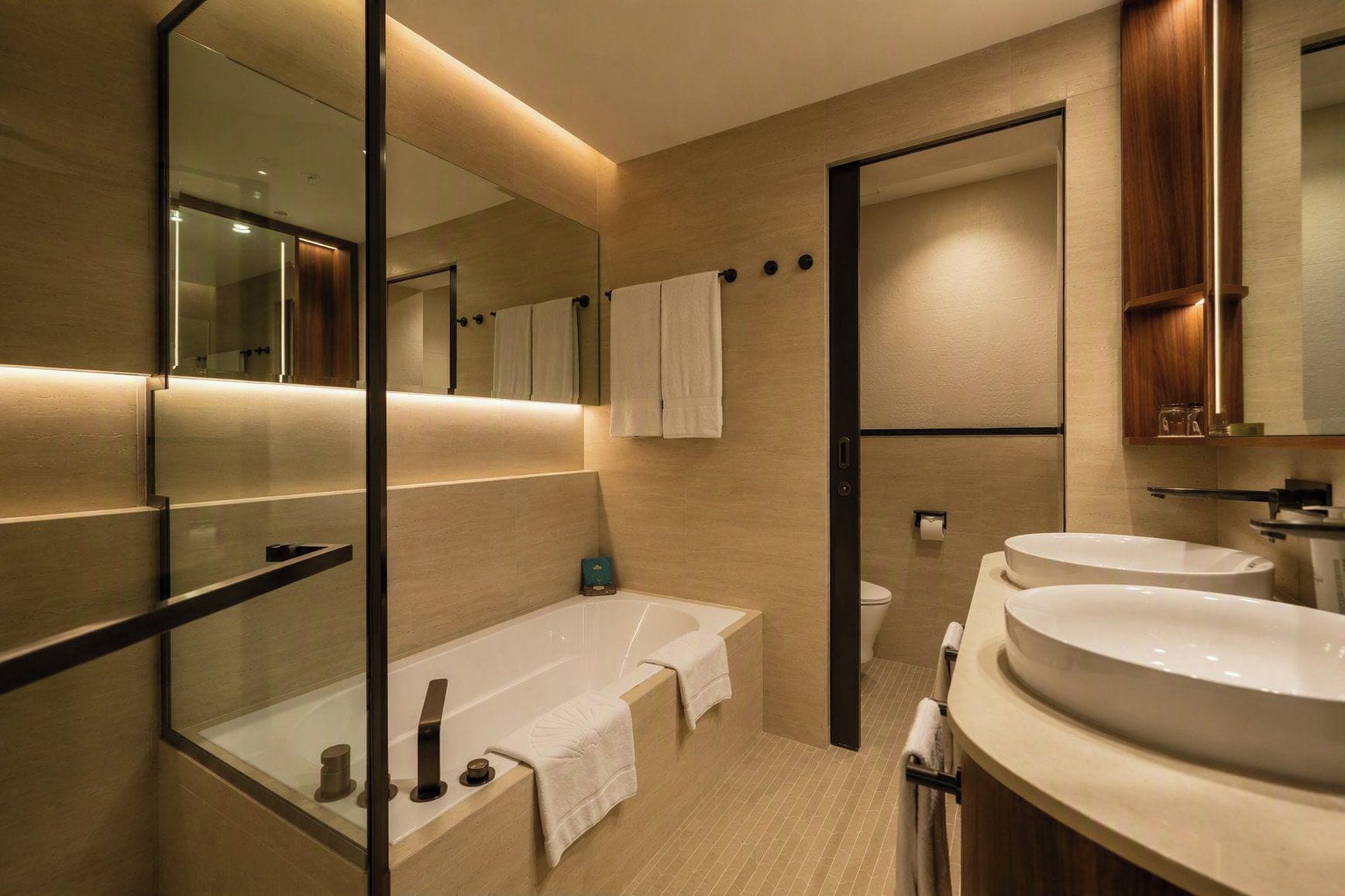 A modern bathroom with a glass shower enclosure, a bathtub, and two sinks.