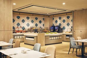 Een modern restaurant met een centraal eiland, diverse zithoeken en een betegelde achterwand.