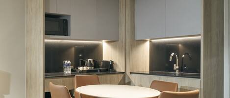 Une cuisine moderne dotée d’appareils électroménagers intégrés, une table de salle à manger ronde avec des chaises, et un four à micro-ondes visible.