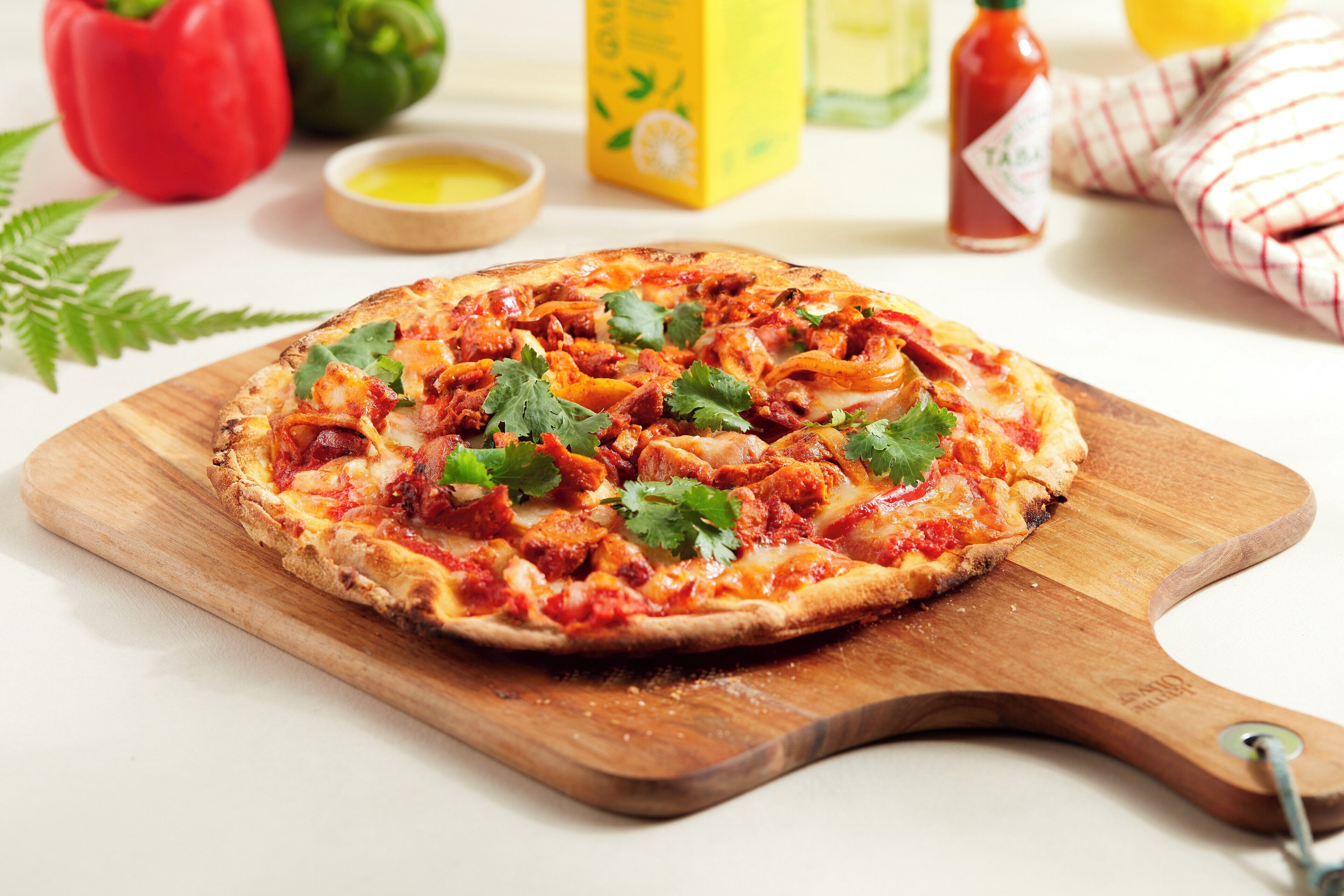 A pizza on a wooden board with a handle.