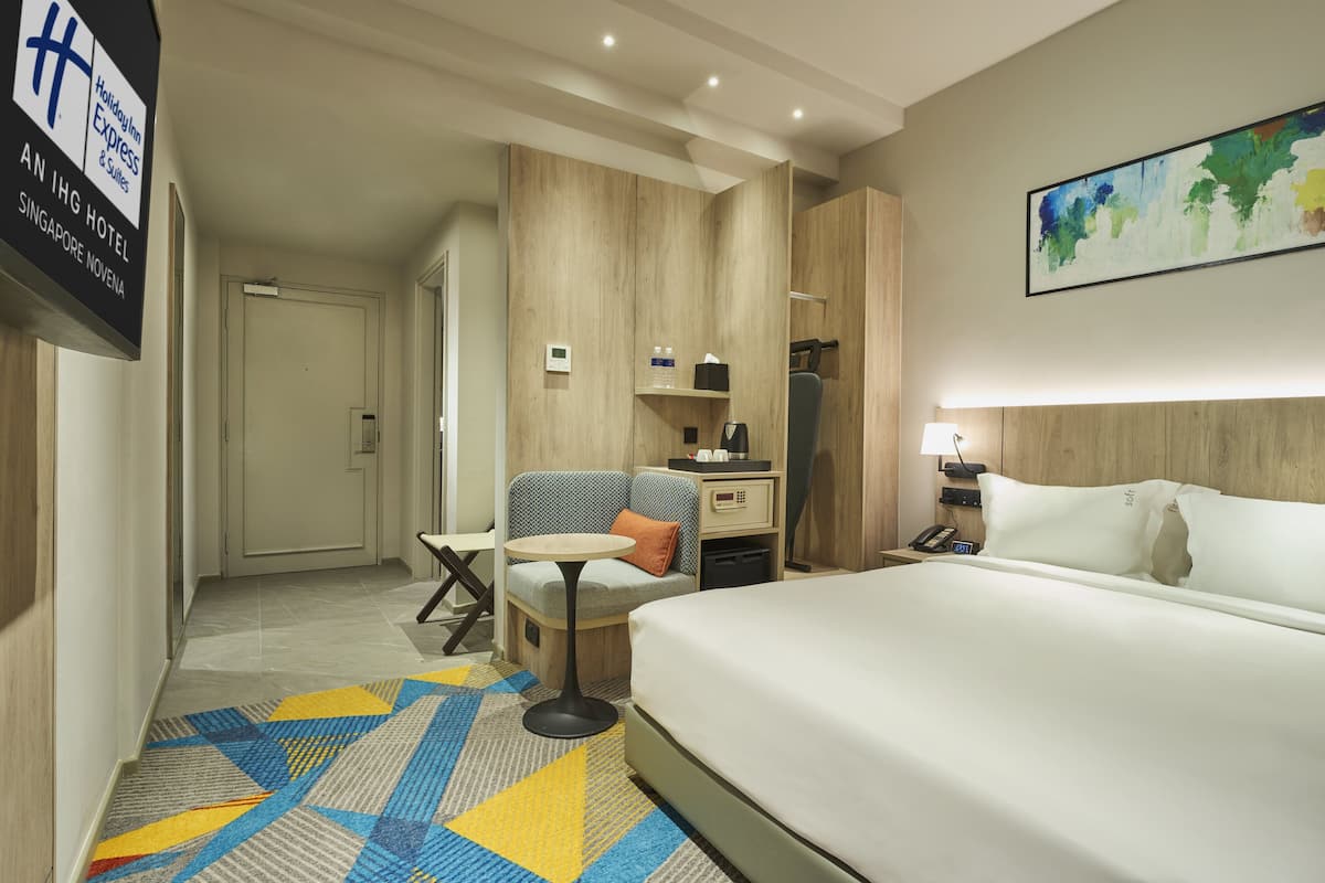 Een hotelkamer met een bed, een bureau, een stoel, een kleine tafel en een schilderij aan de muur.