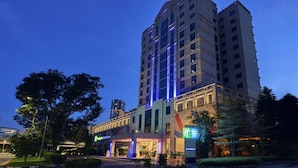 Een hotel met meerdere verdiepingen, een modern gevelontwerp, grote ramen en een opvallende entree met verlichte borden.