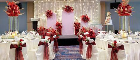 A banquet hall with white tables, red sashes, and floral centerpieces.