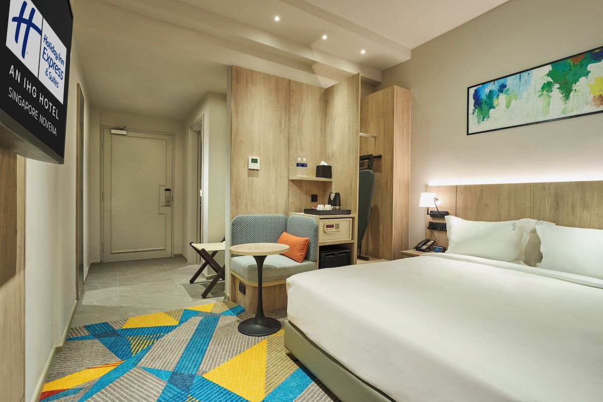 Ein Hotelzimmer mit Bett, Schreibtisch, Stuhl, einem kleinen Tisch und einem Bild an der Wand.