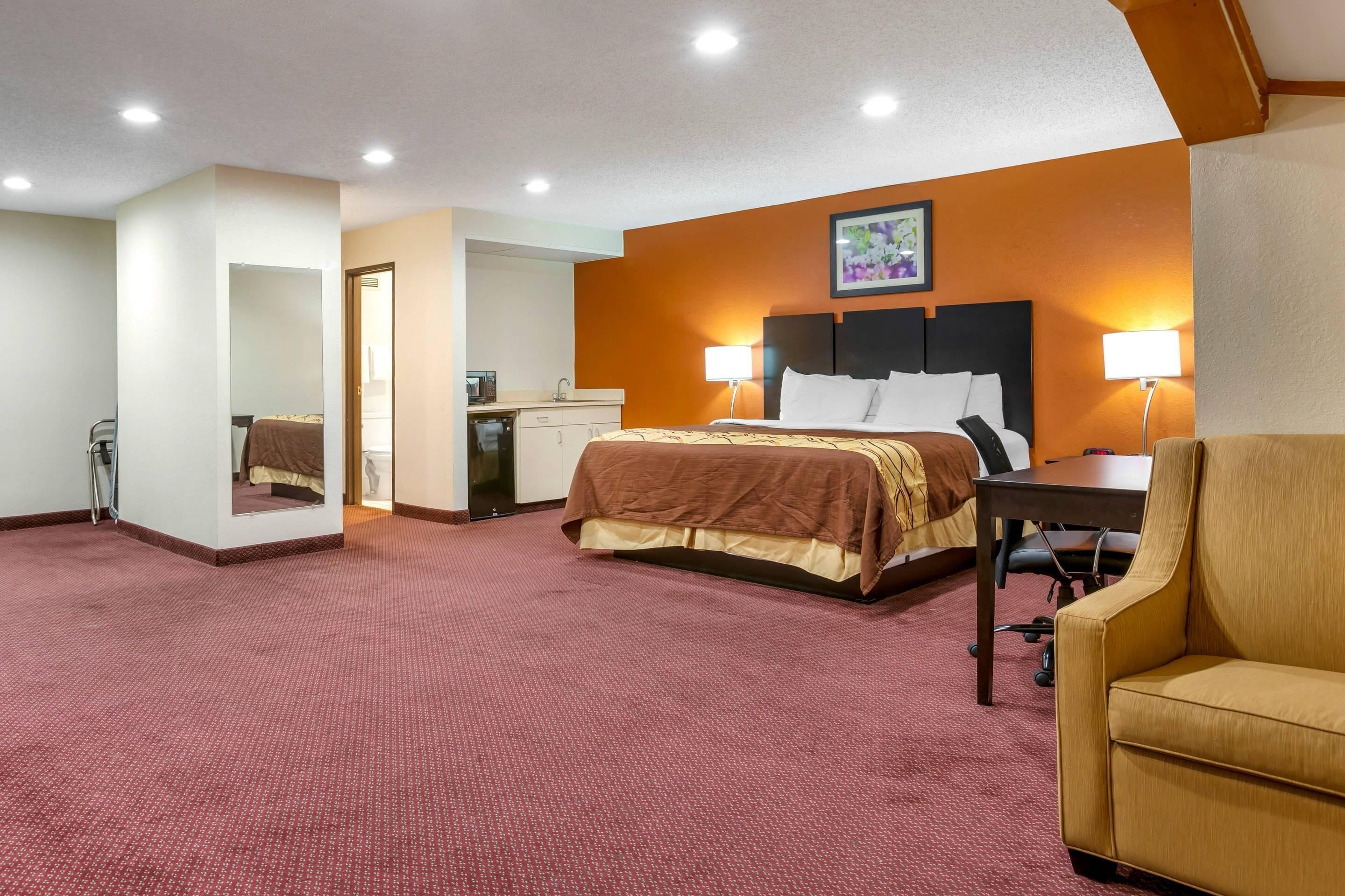 Una habitación de hotel con cama, escritorio, silla y espejo.