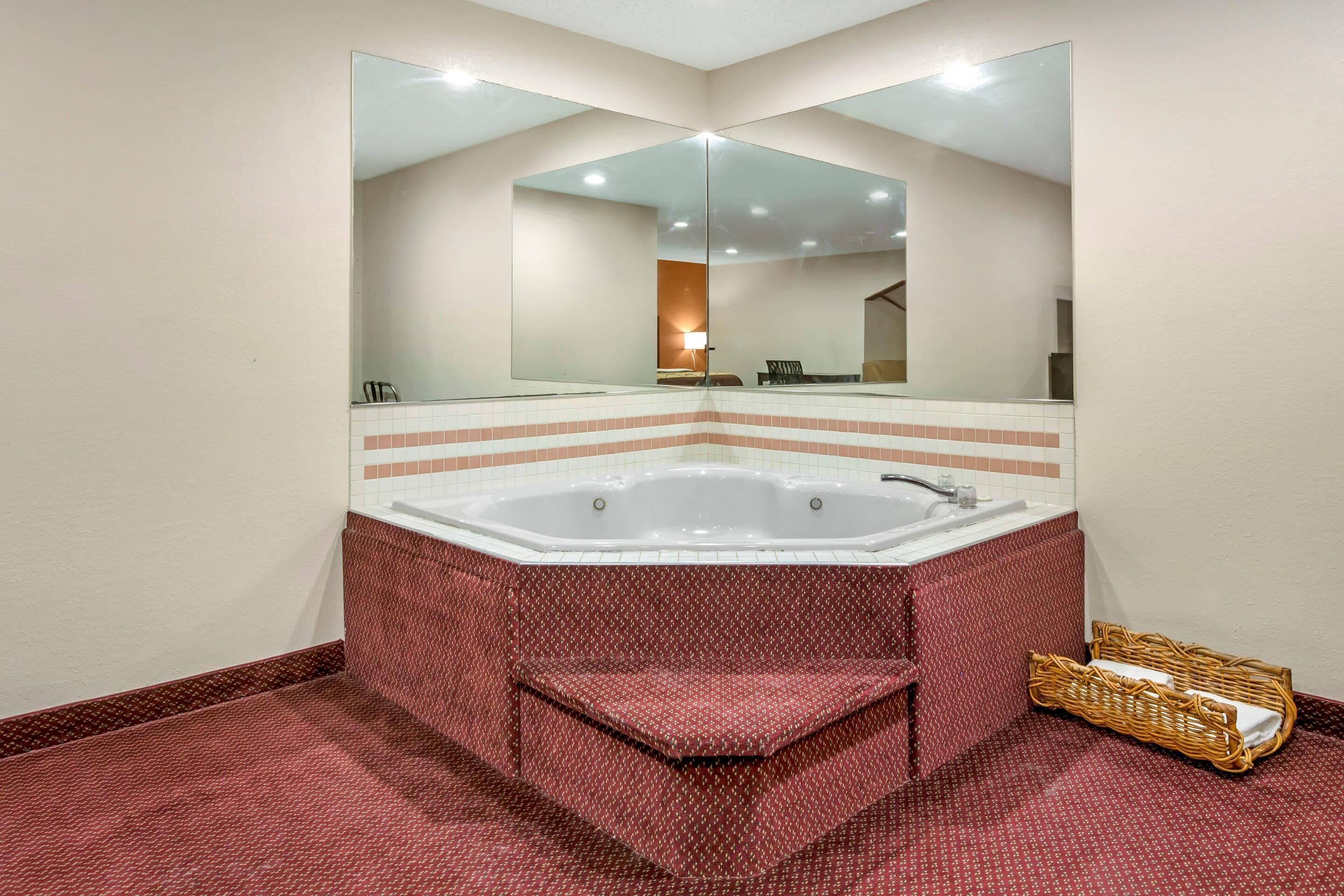 A bathroom with a large bathtub, a mirror, and a wicker basket.