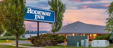 Un letrero de Rodeway Inn con un edificio al fondo.