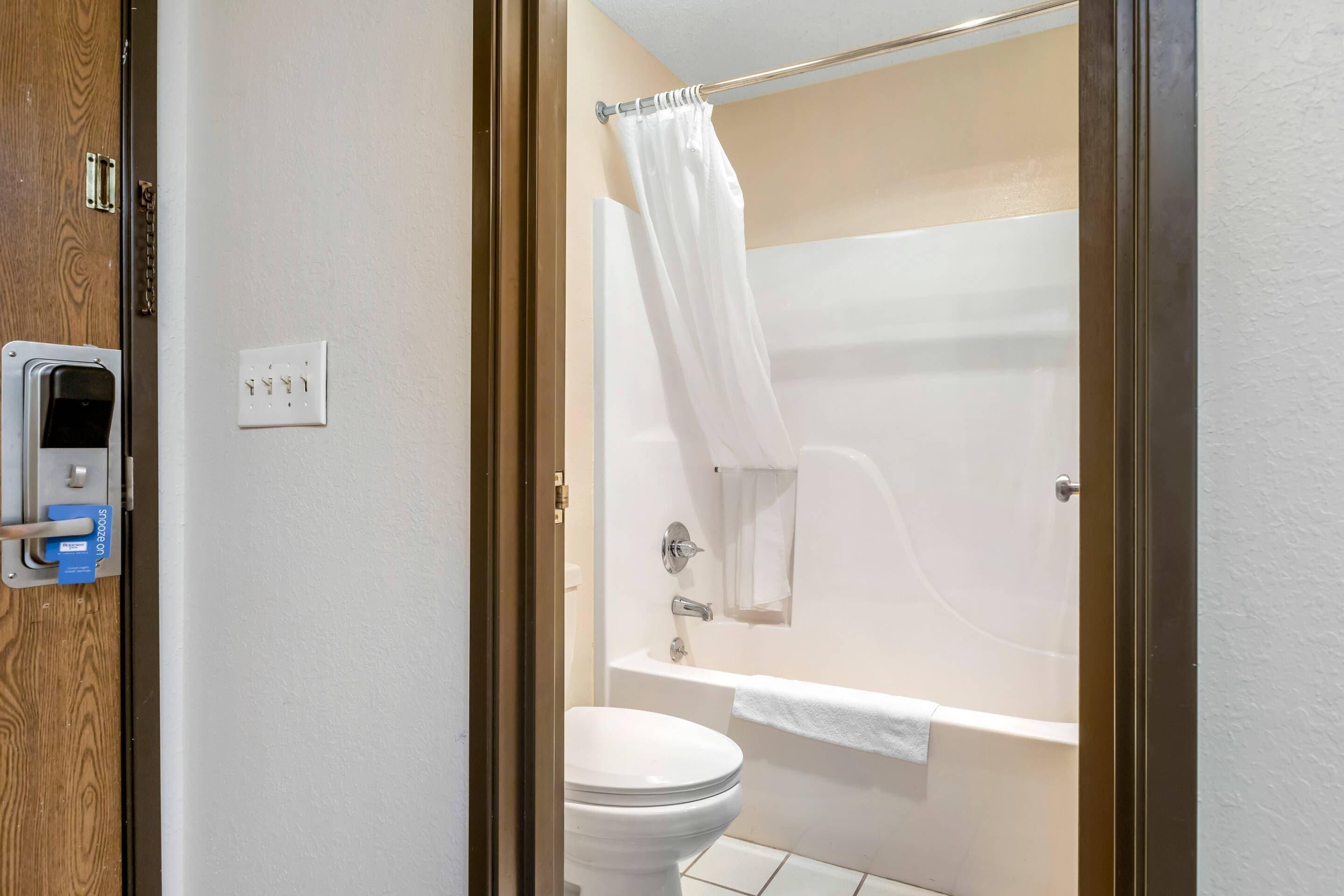 Une salle de bain équipée de toilettes, d’une baignoire et d’un rideau de douche.