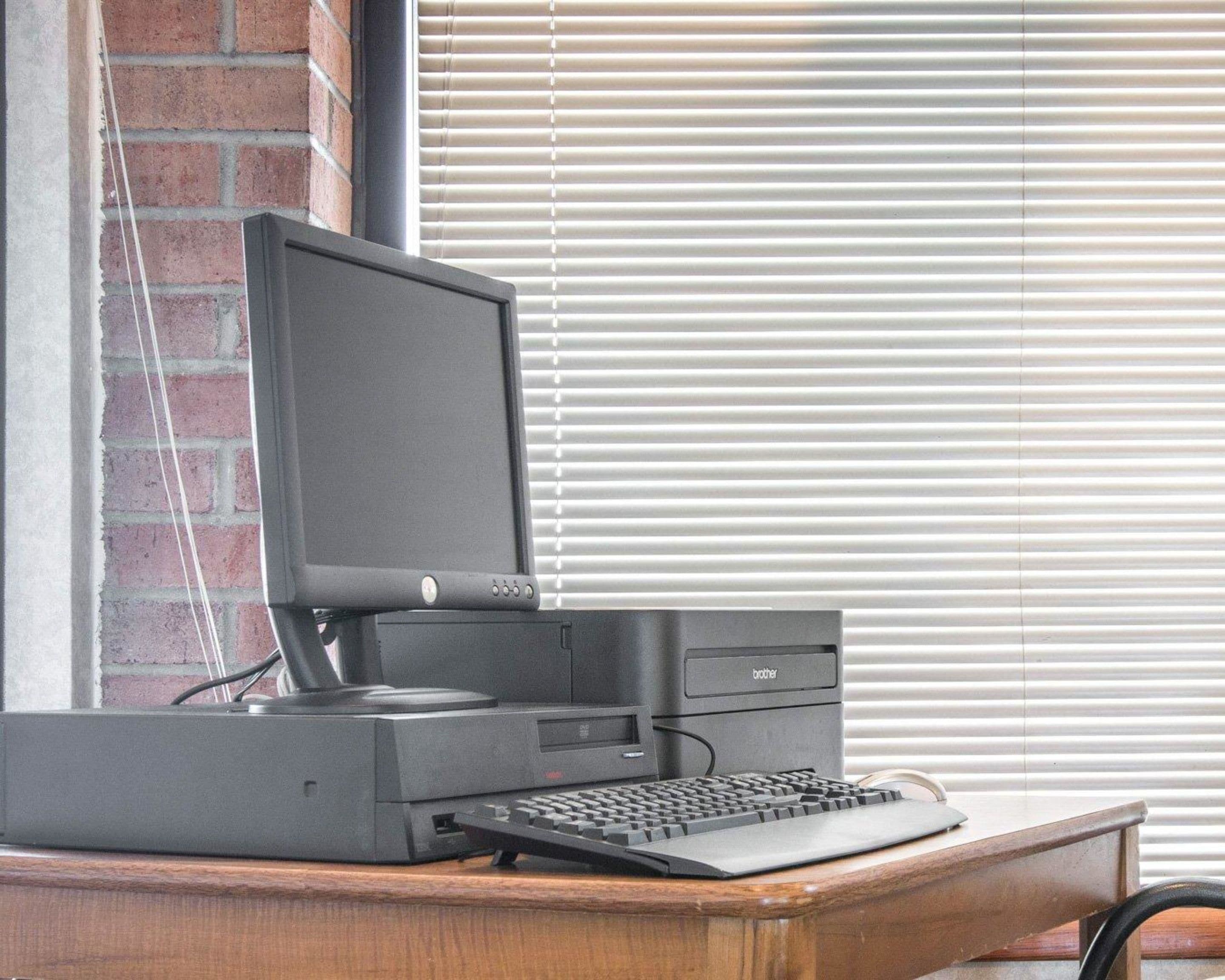 A desktop computer with a monitor, keyboard, and tower on a wooden desk.