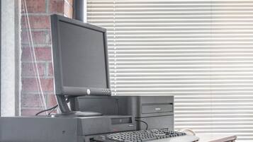 A desktop computer with a monitor, keyboard, and tower on a wooden desk.